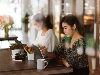 View through glass wall of two female working with office supplies