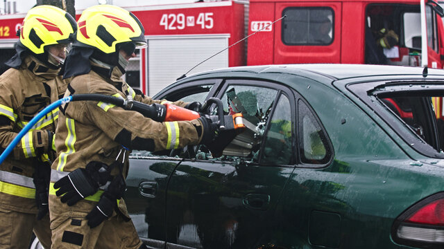 Firefighter beraking glass using jaws of life to extricate trapped victim from the car. High quality photo