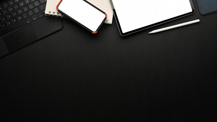 Workspace with tablet, smartphone, supplies and copy space on black table