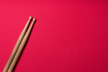 Drum stick on red table background, top view, music concept
