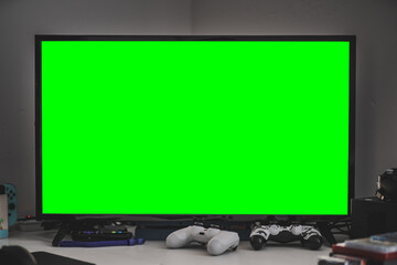 TV w/Green Screen on Desk With Gaming Consoles