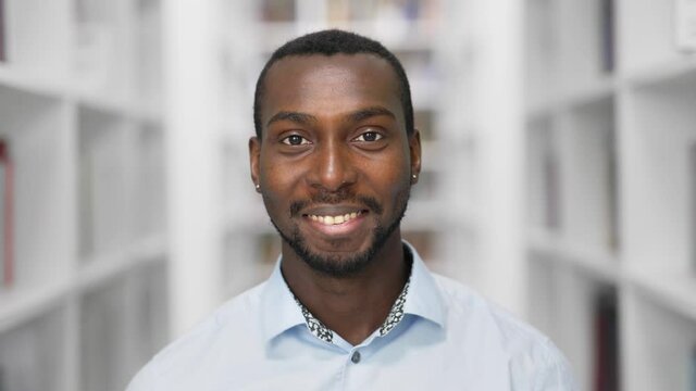 African american man portrait smiling looking at camera standing in library