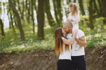 Family in a summer forest. Woman and man in a white t-shirts. Daughter with parents.