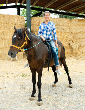 Young woman riding a horse on a farm. High quality photo