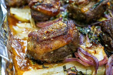 Closeup of a plate of grilled lamb chops with onions and potatoes