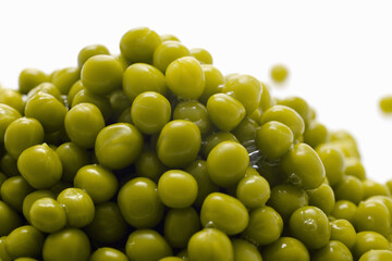 Close-up of a heap of canned green peas on a white background