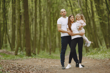 Fototapeta premium Family in a summer forest. Woman and man in a white t-shirts. Daughter with parents.