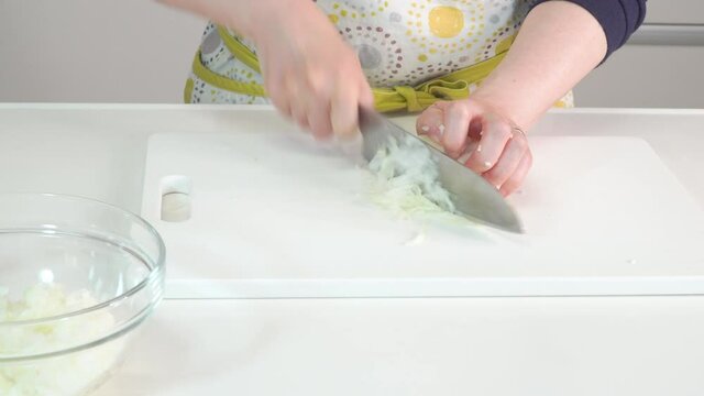 玉ねぎをみじん切りにしていく主婦の調理シーン