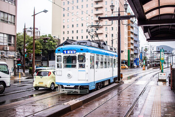 Nagasaki, Japan - 2 November 2020: Blue and white tram on a rainy day in Nagasaki - obrazy, fototapety, plakaty
