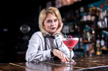 Young girl barman demonstrates his professional skills while standing near the bar counter in bar