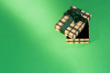 Gift box with a green bow on a green background. One gift box top view on a green paper background. Boxing day