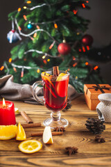 Fototapeta na wymiar Cup of aromatic hot mulled wine on a wooden table on the background of a Christmas tree with lights. Concept of a festive atmosphere