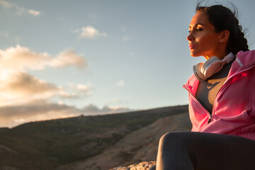 Back view of woman sitting on a mountain top admires the beautiful rising sun over  and enjoys the...