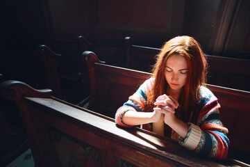 Young Caucasian woman prays in a church. 