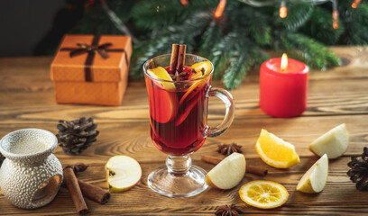 Obraz na płótnie Canvas Cup of aromatic hot mulled wine on a wooden table on the background of a Christmas tree with lights. Concept of a festive atmosphere
