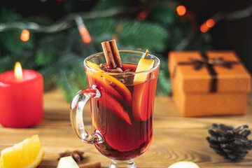 Cup of aromatic hot mulled wine on a wooden table on the background of a Christmas tree with...