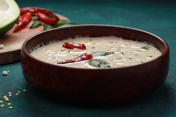 Raw papaya splits with a wooden bowl full of raitha or pachadi ,south indian side dish in meals with its ingrediants on background