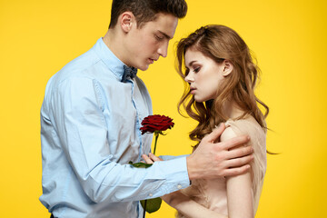 Enamored man and woman with red rose on yellow background cropped view close-up romance