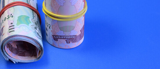 Russian rubles rolled into a tube on a blue background. World economic crisis. Cash loan. Selective focus.