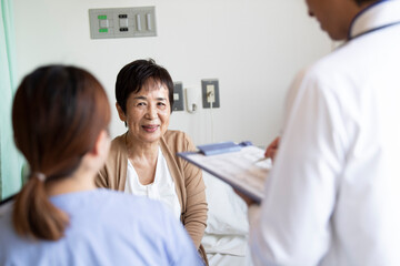 Fototapeta premium 回診に来た医者と話す入院患者の女性と家族