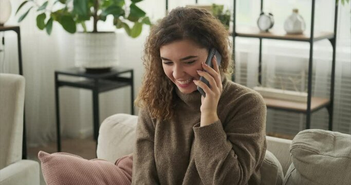 Woman having fun talking on mobile phone at home