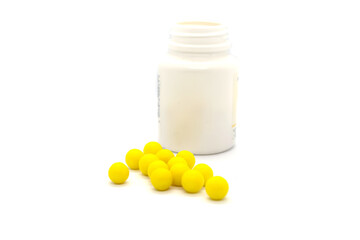 Round yellow pills and plastic jar isolated items on white background.