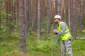 A forest engineer performs forest management work. Forester works in the forest with a measuring tool.