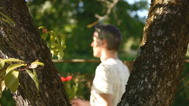 Giving bouquet of flowers outdoor. Handsome  middle aged man giving flowers in summer garden, between trees.