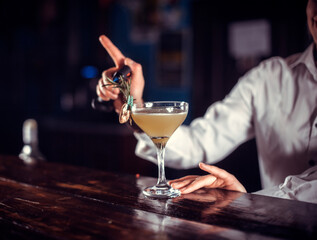 Confident woman bartender demonstrates the process of making a cocktail at the night club
