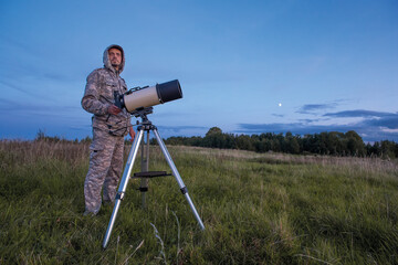 A male astronomer observes the sky through a telescope. Amateur astronomy concept.