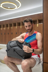 Young man in bright tshirt sitting and unzipping his bag