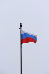 Russian flag on a light sky background, white, blue and red tricolor