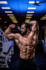 Fototapeta na wymiar strong young athlete with beard showing sport physique in athletic workout gym
