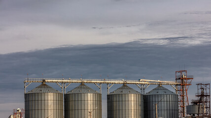 Low angle shot of grain storage units. Grey cloudy sky as a background. Altai Krai, Siberia, Russia