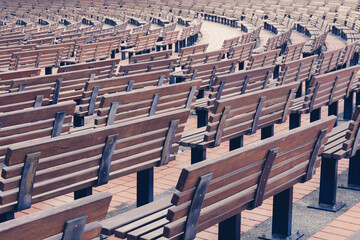 Rows of wooden benches in the park. Benches arranged in curved lines. Toned image.