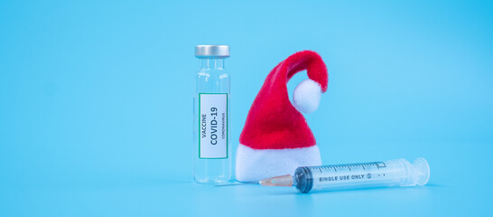 COVID-19 Vaccine vial, injection Needle Syringe and Santa Clause hat against Coronavirus infection...