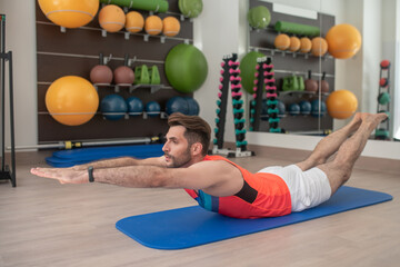 Bearded male bending his back, lifting hands and feet