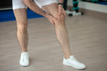 Close-up of male hands massaging painful knee in the gym