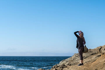 Woman standing on cliff looking onto the pacific ocean in Bodega Bay Northern California