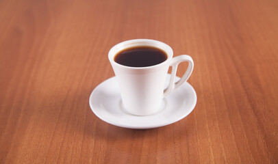Coffee in a white cup is isolated on a wooden background.