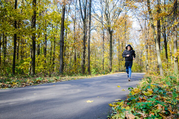 Obraz premium Caucasian middle aged man running outdoors under trees autumn time in the park