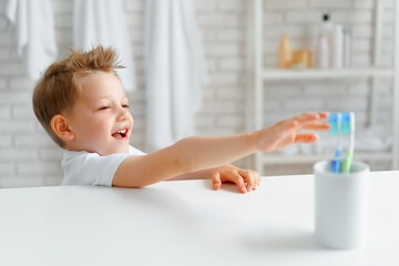 Little boy reaching out for toothbrush in bathroom