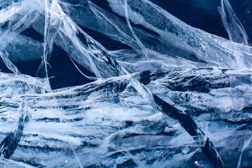 Large deep cracks in the ice of the lake. Blue thick and transparent ice. Horizontal.