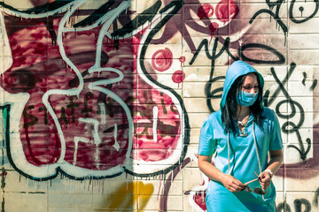 Woman in face mask near the wall with graffiti