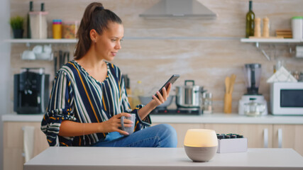 Woman enjoying aromatherapy with essential oils diffuser working while she drinks coffe. Aroma...