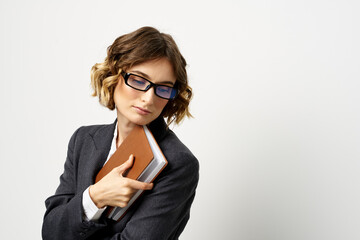 Woman at work with book in hand light background classic suit glasses head