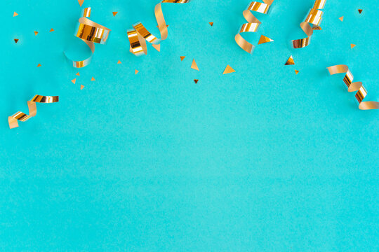 close up on group of gold color of rolling ribbon and confetti on teal background with copy space for christmas festival happy new year ,carnival , birthday and anniversary, concept design	