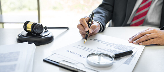 Male lawyer or judge working with contract papers, Law books and wooden gavel on table in...