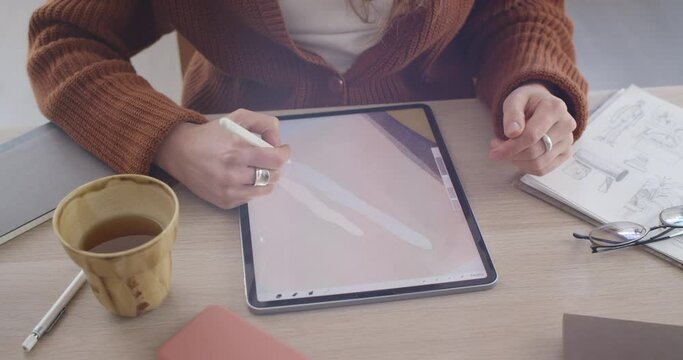Crop view of female graphic designer creating illustration on tablet and rotating screen.Talanted illustrator using digital pad and stylus while sitting at workplace . Concept of art