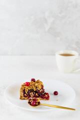 A slice of cranberry pie on a white plate with a cup of tea. Sugar, gluten and lactose free.